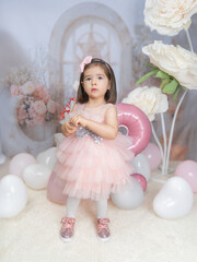 Generated A little girl in pink clothing celebrates in a fairy-tale setting with pastel decorations, a large pink balloon in the shape of a two, and white flowers, radiating joy and innocence.