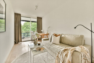 A stylish, modern living room showcasing minimalistic decor, featuring a cozy couch, wooden table, and large windows for natural light.