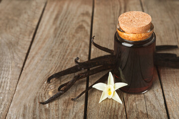 Vanilla extract in glassware on a wooden table. Vanilla extract for baking and desserts. Aromatic Homemade Vanilla Extract. Close -up. Place for the text. Copy space.
