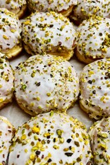 close up of white glazed donuts sprinkled with pistachios. side view. fat thursday