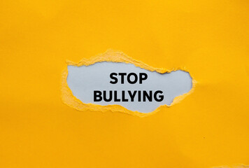 Stop bullying message written on ripped torn yellow paper on gray background. Conceptual stop bullying symbol. Copy space.