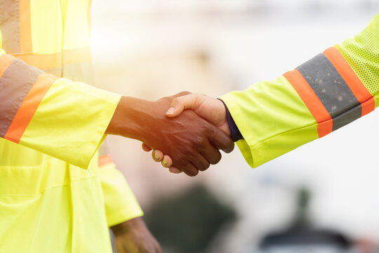 Unity and teamwork concept. Male workers standing and hands shake together. Completed finish job. Successful of work - Powered by Adobe