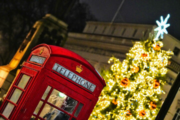 Obraz premium Christmas Decorations With A Red Telephone Box, Iconic Red Phone Booth In Central London, Christmas Lights, Christmas Tree, Regent Street St James, West End, England, United Kingdom