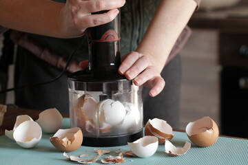 Preparing Eggshell Powder. Woman grinds eggshells with blender. Calcium supplement, cracked eggshell, natural compost ingredient, broken eggshell