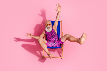 Photo of good mood senior man wear swimwear relax rest chaise lounge summer resort isolated on pink color background