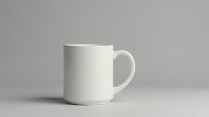 Obraz premium A simple white ceramic mug, cylindrical in shape, with a single handle, rests on a neutral background, providing a clean and minimalist aesthetic.