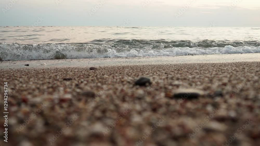 Poster Soft waves roll onto a sandy beach as twilight sets in. Calm sea reflects the fading light, creating a serene atmosphere for evening relaxation. Reflection of yellow rays. Mediterranean Adriatic Sea