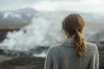 Fototapeta premium A woman gazes at a misty volcanic landscape, feeling the vastness of nature.