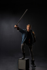young student in a denim jacket and maroon sweater stands confidently in a studio, holding books...