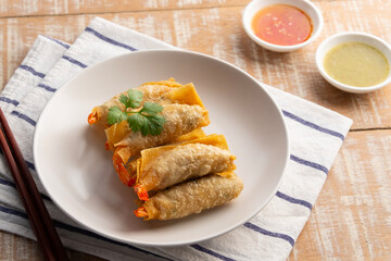 Deep Fried Crispy Wonton wrapped with shrimp and minced pork in white plate.Thai appetizer food with Sweet Chili Sauce and seafood sauce.
