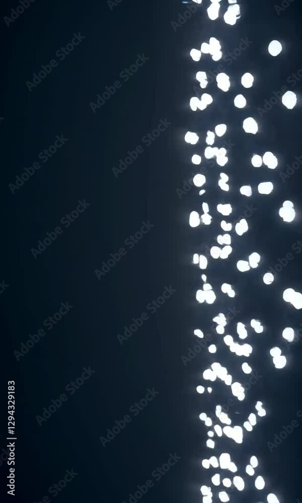 Poster luminous particles cascading down dark background in vertical motion sequence