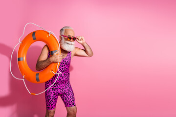 Photo of serious focused life guard man look empty space with orange lifebelt wear dotted swimsuit...