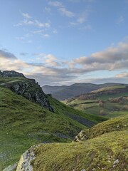 Beautiful Llangollen landscape with green hills and rocky terrain under a soft blue sky. Ideal for travel and nature projects. Captured in natural autumn light.