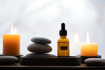 Spa still life with essential oil in glass bottle, candles on background window.