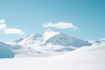 Obraz premium Snow-covered mountain range under a pale blue sky with scattered clouds, a serene winter scene
