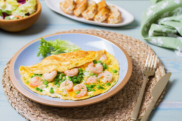 Prawn omelette with green peas on blue plate. Eggs with shrimps