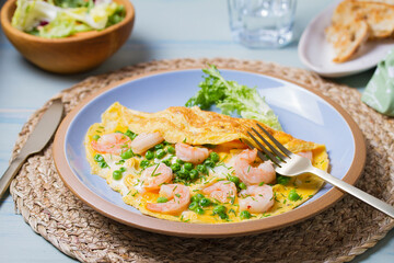 Prawn omelette with green peas on blue plate. Eggs with shrimps