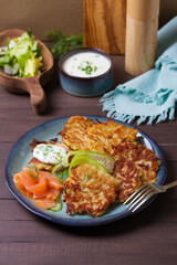 Potato hash browns with smoked salmon and cucumbers. Potato cakes or vegetable fritters, patties. View from above, top view
