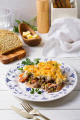 Shepherd's Pie or Cottage Pie on white plate. Savory pie made with beef mince and vegetables topped with mashed potatoes and cheese