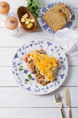 Shepherd's Pie or Cottage Pie on white plate. Savory pie made with beef mince and vegetables topped with mashed potatoes and cheese. View from above, top view