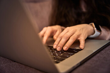 female hands typing on laptop computer on sofa, internet network communication