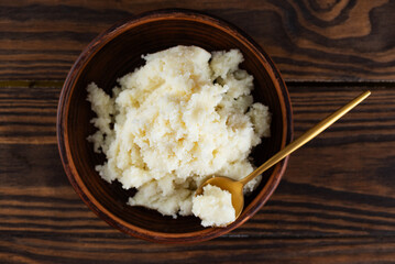 Edible shea butter in a clay plate on wooden table. Top view.