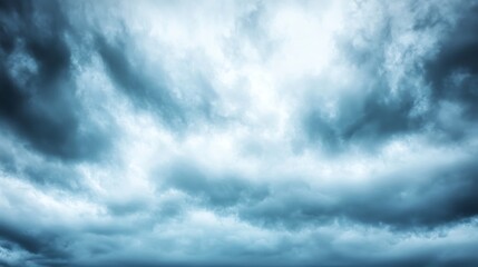 Obraz premium An overcast sky with dark clouds scattered across, letting only a subtle light pass through, creating a soft, muted atmosphere.