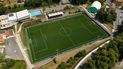 Aerial view of a soccer field with synthetic grass in a sports center with a swimming pool.