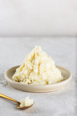 Shea butter in a bowl on a light background. Vertical orientation.