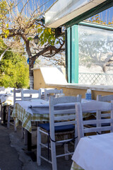 Tables covered with checkered tablecloths are waiting for visitors in the open air near the cafe terrace