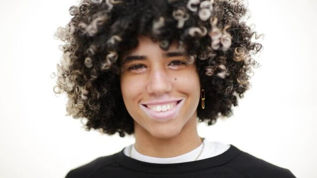 Video of a teenager with curly natural hair and vitiligo skin smiling while looking at the camera - Powered by Adobe