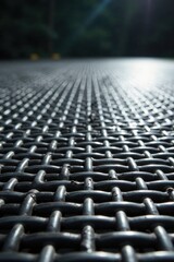 Obraz premium A Detailed Close-Up View of Interwoven Metal Mesh Surface Showing a Pattern of Regularly Spaced Grids Under Sunlight