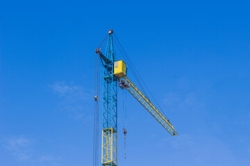 Construction crane operating under clear blue sky at a busy construction site