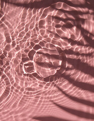 Pink water texture background on the noon sunlight with tropical leaves shadow.