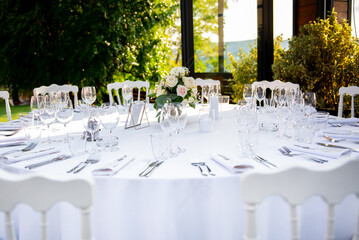 Elegant round dining table set for a sophisticated outdoor gathering, adorned with delicate floral arrangements and sparkling glassware