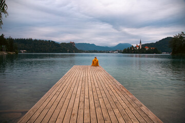 Man sitting on wooden deck, pier at Bled lake, Slovenia