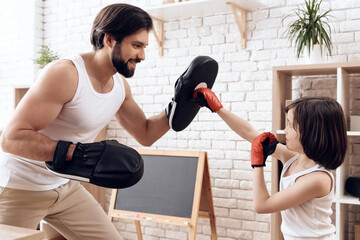 Athletic bearded father teaches son to box.
