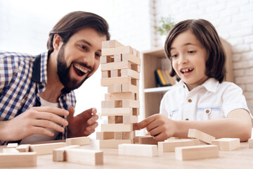 Close up. Bearded father with small son plays Jenga at home.