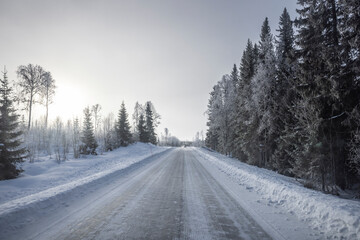 Fototapeta premium Verschneite Landstrasse mit Schneefahrbahn im Winter