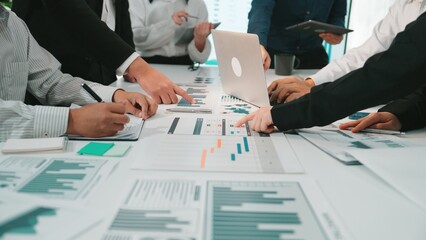 A diverse business team actively collaborating over charts and data in a modern office setting....