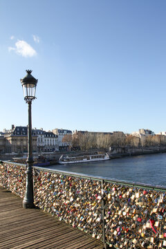A fence with many locks on a bridge in Paris. in the background you can see a lamppost