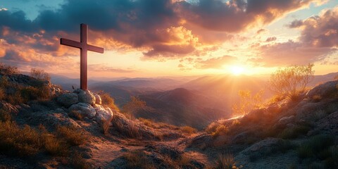 Sunset over a mountainous landscape featuring a wooden cross on a rocky terrain with soft clouds in the sky