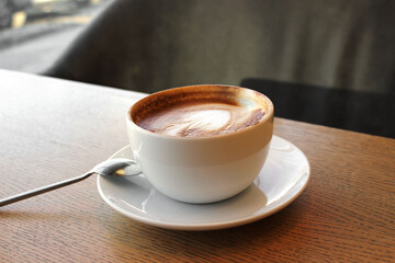 Cup of cappuccino on wooden table in cafe