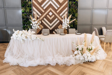 Reception table decorated with roses. Bride and groom presidium