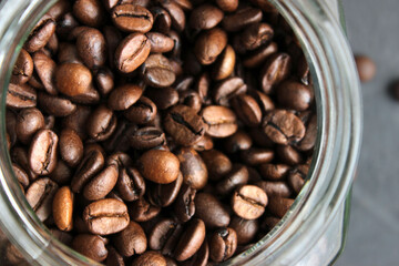 Arabica coffee beans in a glass jar on a dark table