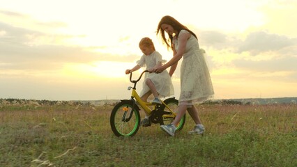 happy family. child girl learning ride bike. mom daughter kid spend time bike park. concept children dream. mother child play outdoors. little girl pedals steers bicycle park. young mother with kid