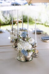 silver candlesticks, flowers and vases on a table decorated in a restaurant on the terrace outdoors