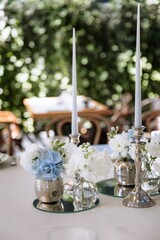 silver candlesticks, flowers and vases on a table decorated in a restaurant on the terrace outdoors
