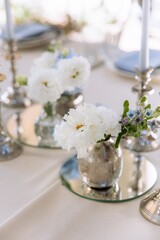 silver candlesticks, flowers and vases on a table decorated in a restaurant on the terrace outdoors