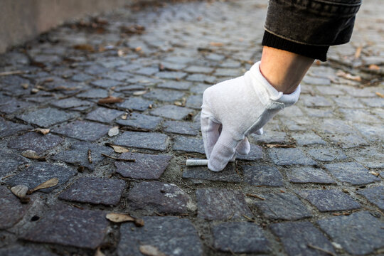 Male hand collecting cigarettes. Cleaning streets from a garbage. The concept of ecology, environment, garbage, negative impact on nature. Urban pollution. Cigarette butts.